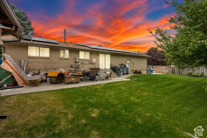 Brick exterior, concrete patio, solar panel array, and lawn space