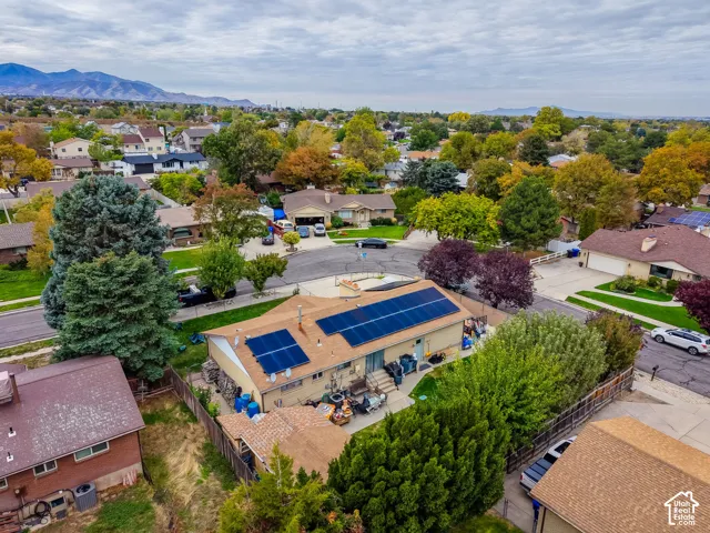 Exterior perspective featuring a roof-mounted solar panel system, masonry chimney, and established perimeter landscaping, with mountain range backdrop