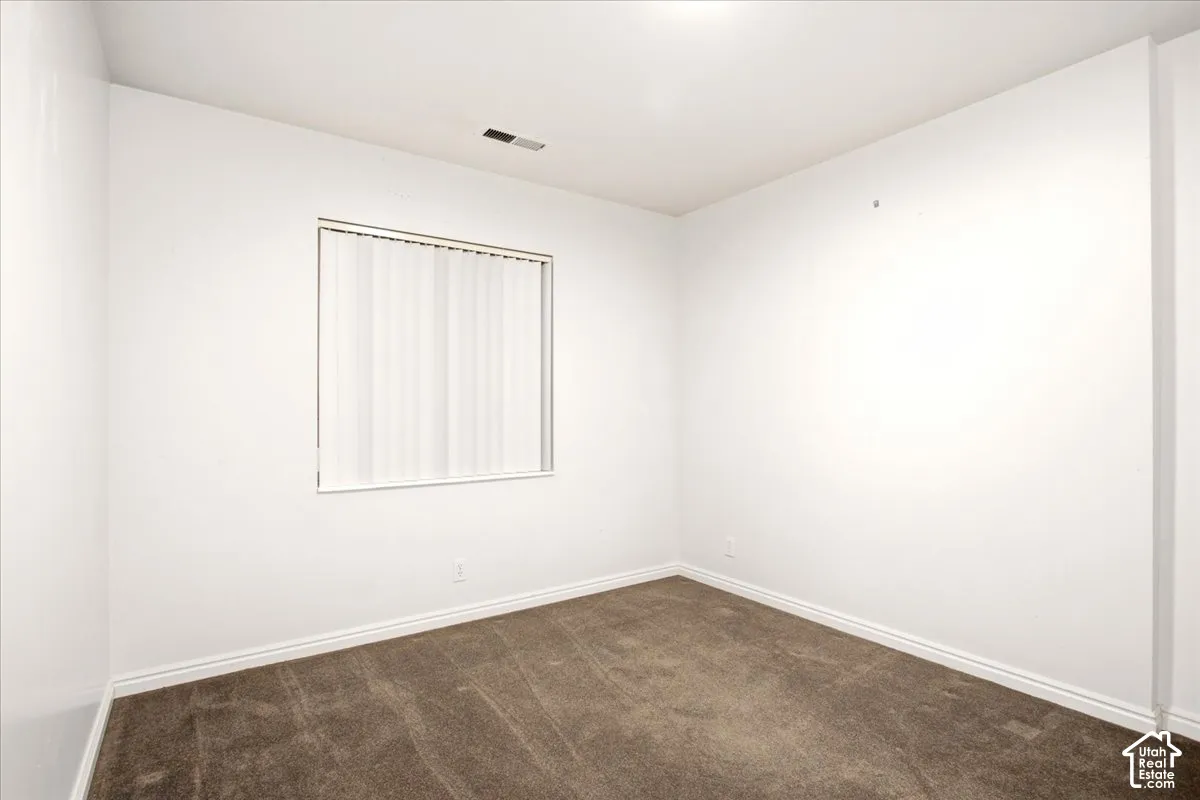Room featuring neutral wall paint, carpeted flooring, and a window with vertical blinds