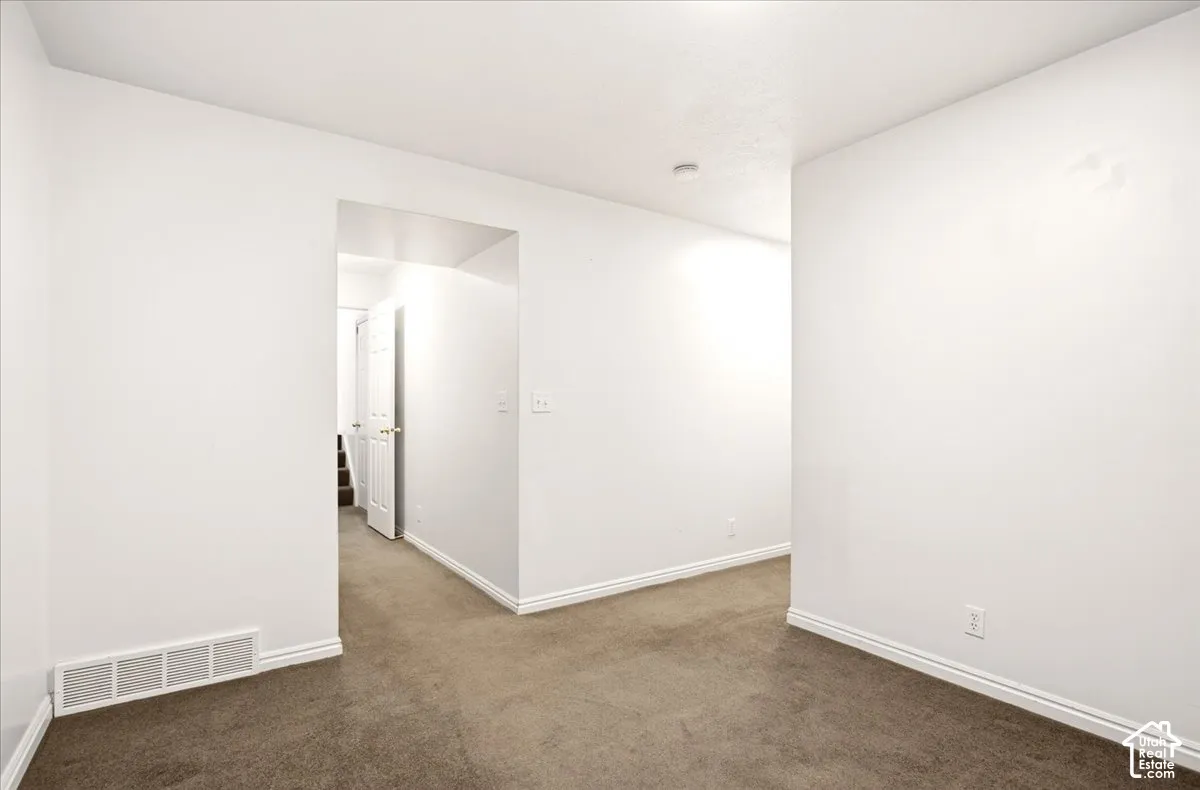 Neutral wall-to-wall carpeting and crisp white interior walls with an open-entryway layout