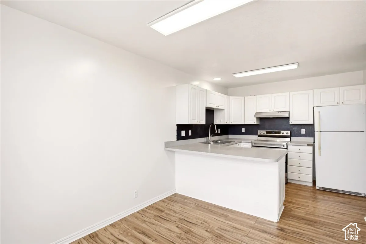 Kitchen featuring white cabinetry, wood-finish flooring, a breakfast bar, and stainless steel appliances