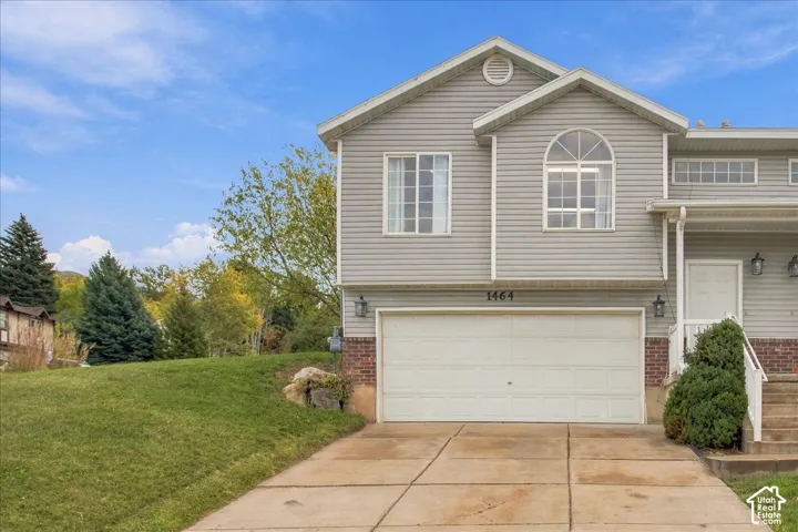 Exterior featuring horizontal siding, brick masonry detailing, an arched window, a concrete driveway, and an attached two-car garage