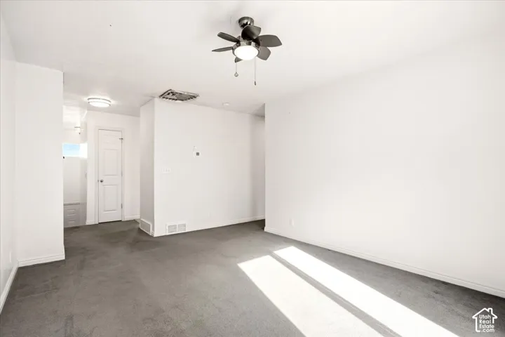 Neutral-toned wall-to-wall carpeting, multi-blade ceiling fan with integrated lighting, and a solid-core interior door