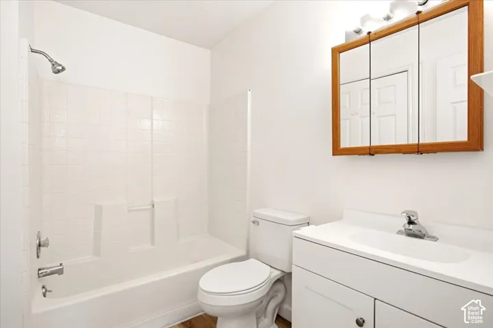 Bathroom featuring a white vanity cabinet with an integrated sink, a wood-framed medicine cabinet, and a shower-tub combination with a tiled surround