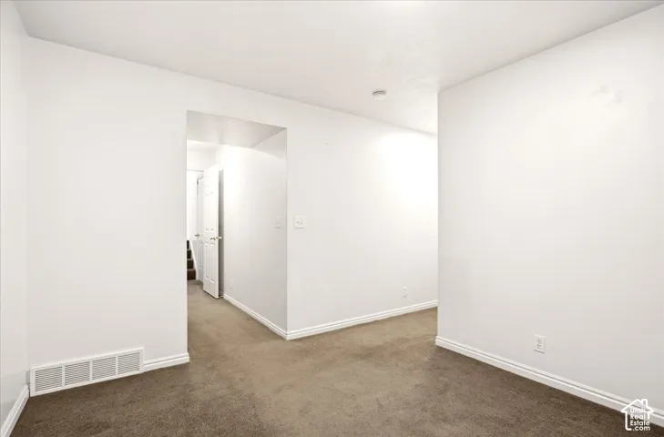 Neutral wall-to-wall carpeting and crisp white interior walls with an open-entryway layout