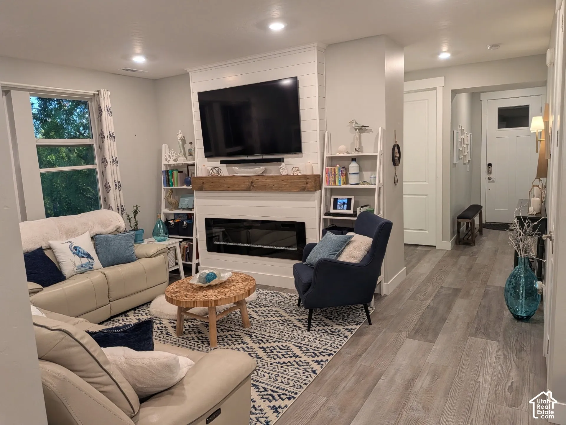 Living area featuring a horizontal shiplap fireplace surround, recessed lighting, wood-finish flooring, and a natural timber mantel