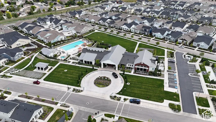Aerial perspective of community facilities featuring an outdoor swimming pool, spa, circular driveway, landscaped lawn, and dedicated parking area