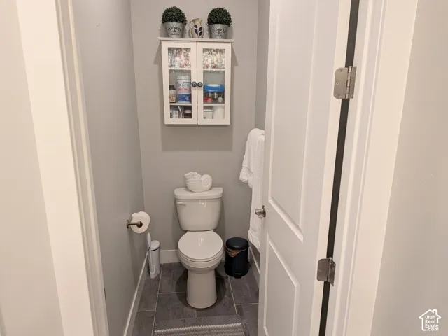 Built-in white wall-mounted cabinet with glass doors, neutral-toned walls, and grey tile flooring