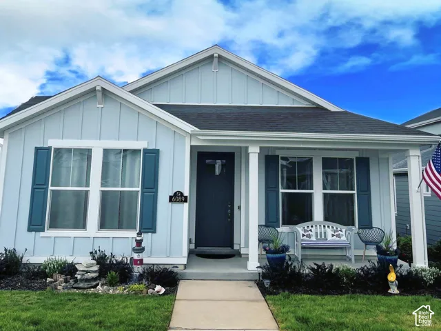 Board and batten siding, gable roofline with decorative brackets, covered front porch with square columns, and contrasting window shutters