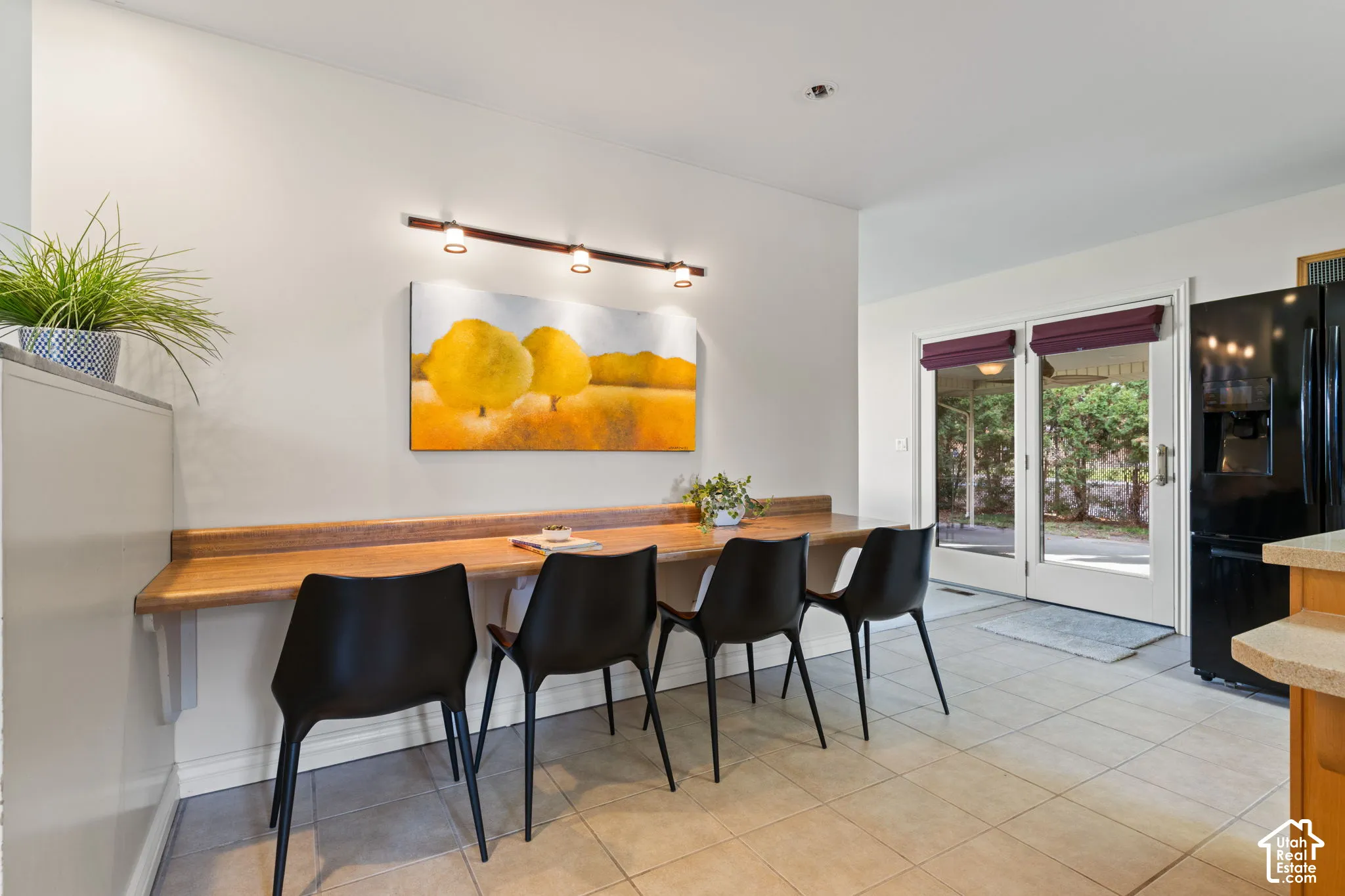 Built-in wood-topped breakfast bar with track lighting and large-format tile flooring, featuring double glass-paneled patio doors