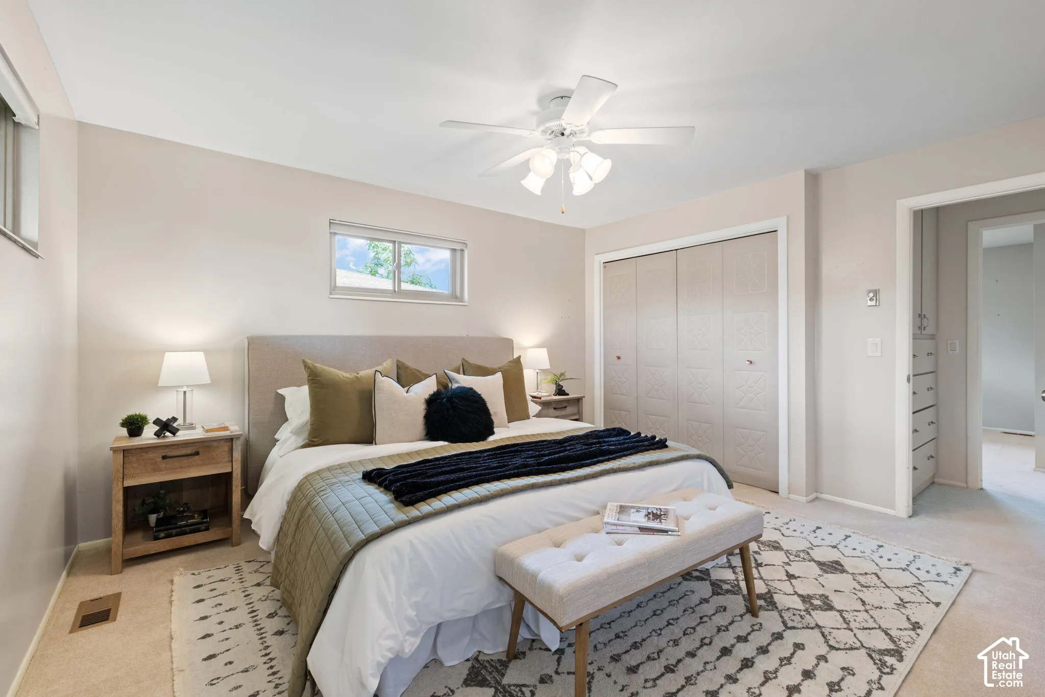 Neutral-toned walls, ceiling fan with integrated lighting, horizontal sliding window, and bi-fold closet doors
