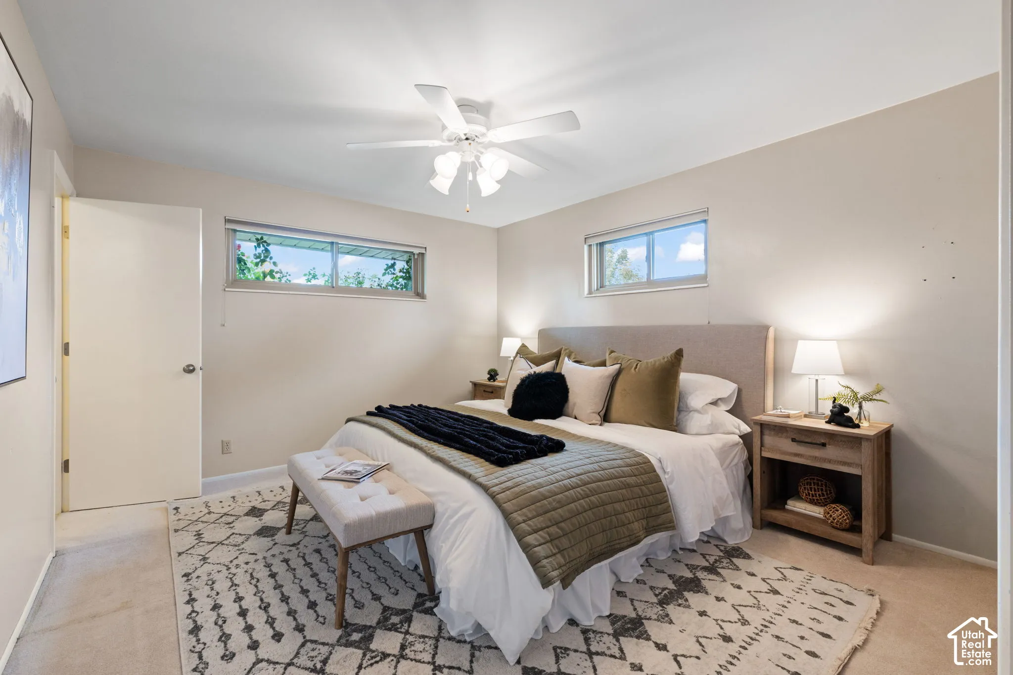 Neutral-toned walls, ceiling fan with integrated lighting, dual horizontal windows, and carpeting