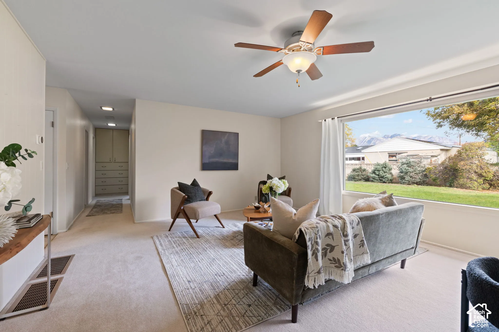Large picture window, ceiling fan with light fixture, and built-in hallway cabinetry