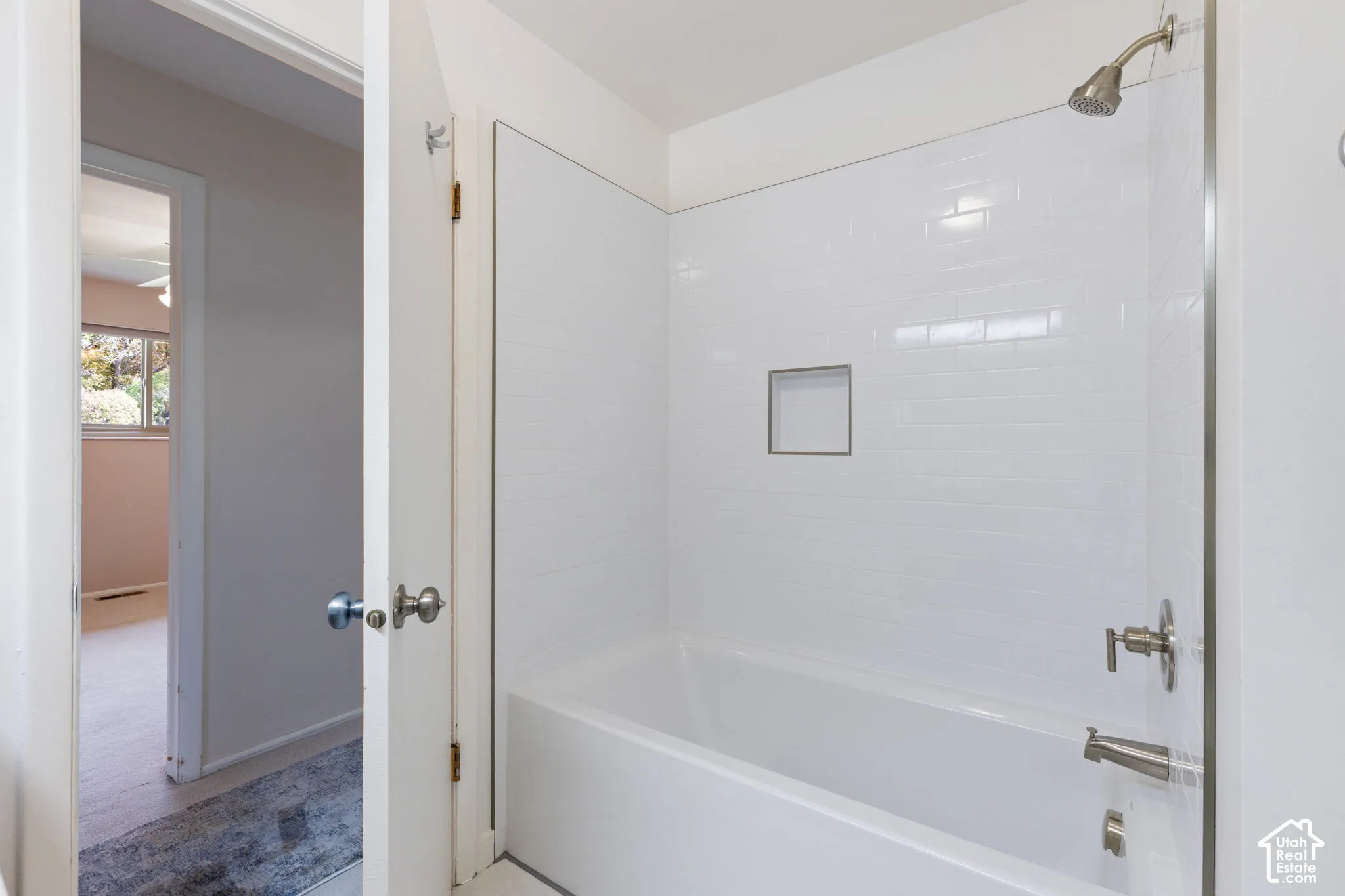 Bathtub with white subway tile surround, integrated tiled niche, and brushed nickel hardware