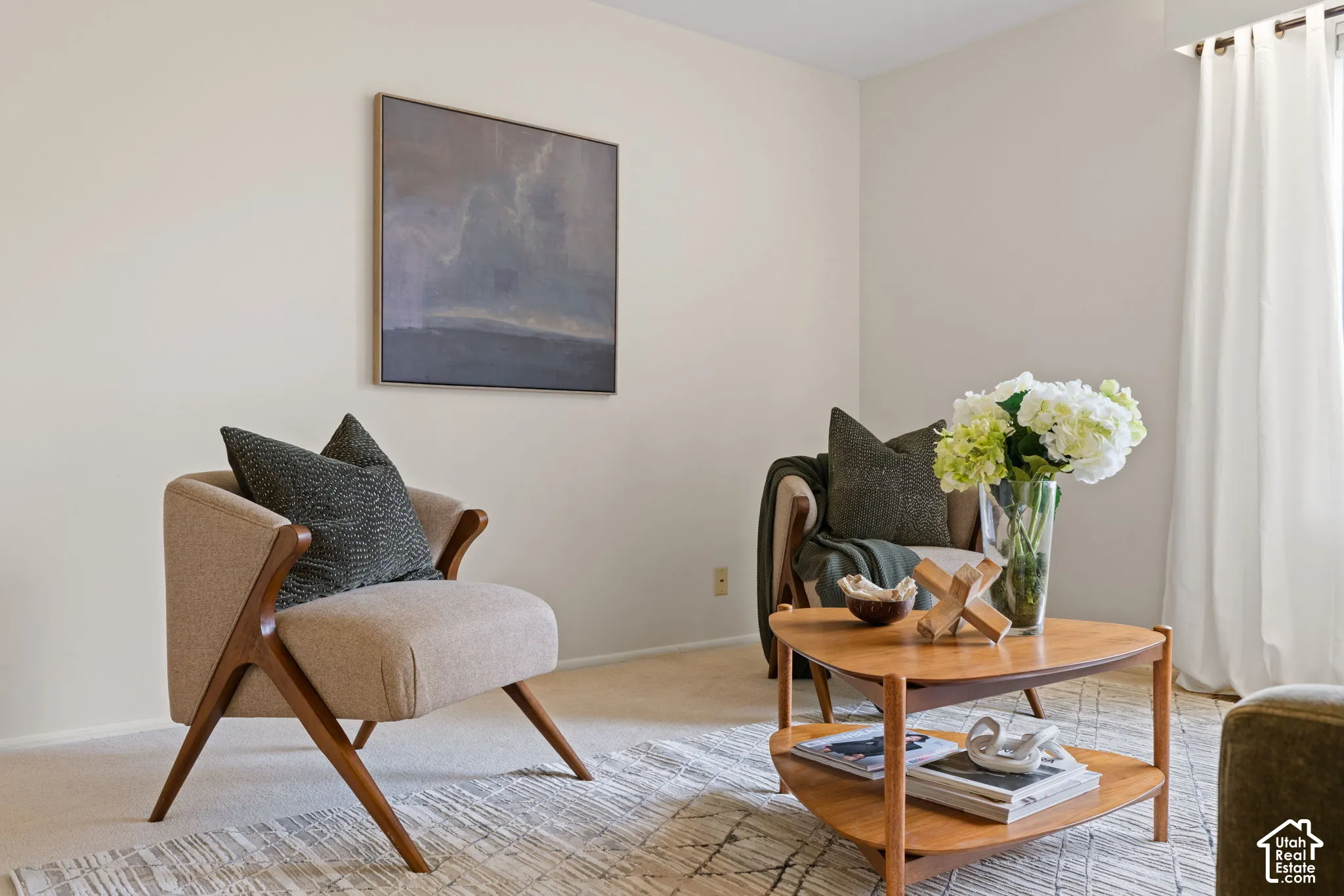 Neutral-toned interior space featuring light-colored carpeted flooring, finished walls, and a window treatment