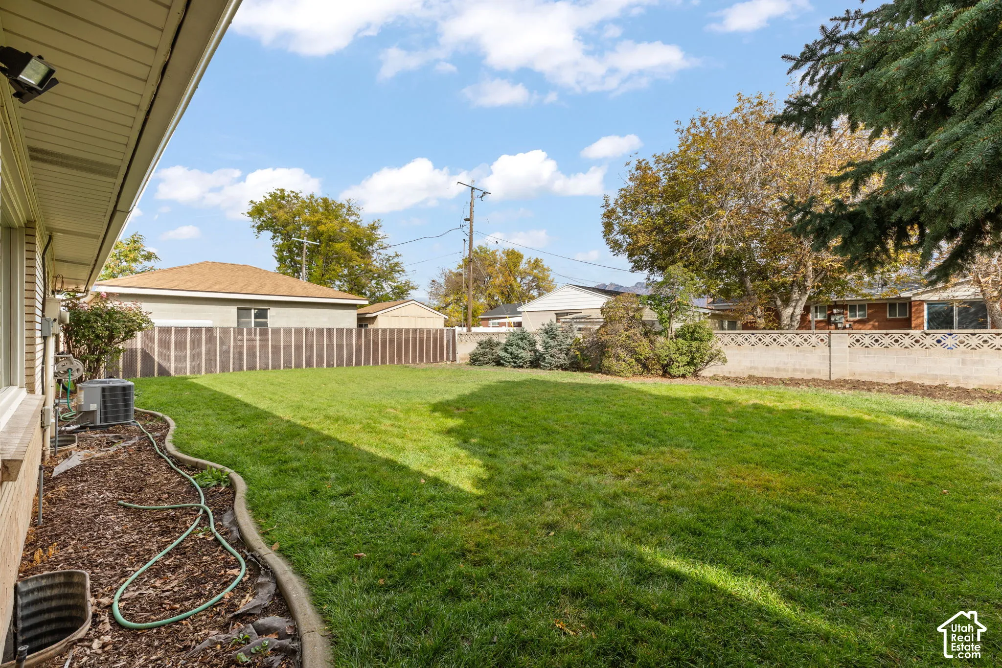 Backyard featuring a manicured lawn, concrete curbing, mature trees, and perimeter masonry fencing
