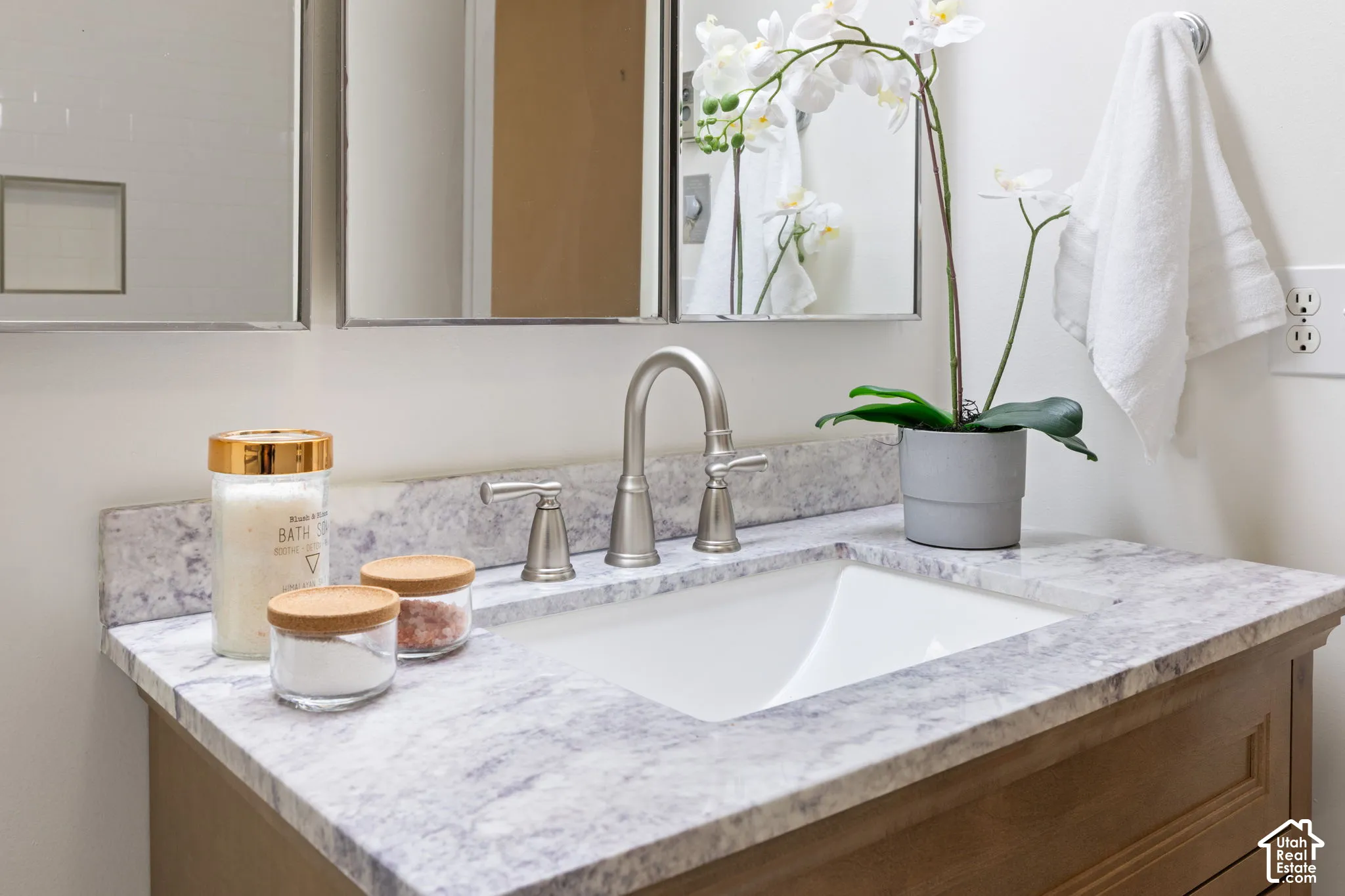 Vanity featuring a stone-composite countertop, undermount sink, brushed-nickel widespread faucet, wood-finish cabinetry, and inset medicine cabinet mirrors