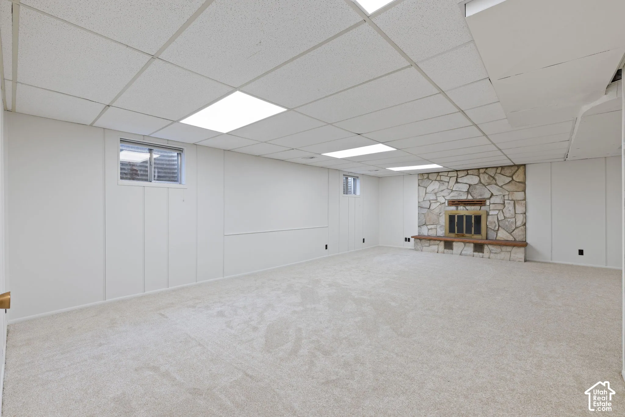 Expansive room featuring wall-to-wall carpeting, recessed ceiling lighting, and a floor-to-ceiling stone fireplace with a built-in hearth