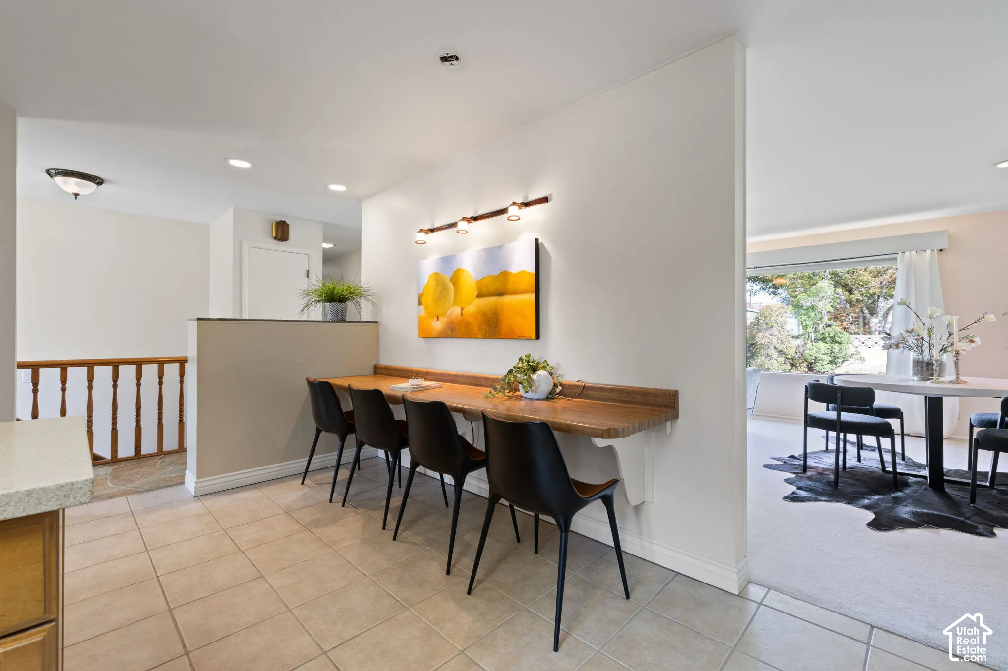 Built-in wooden wall-mounted desk, recessed lighting, tile flooring, and decorative three-bulb wall-mounted fixture