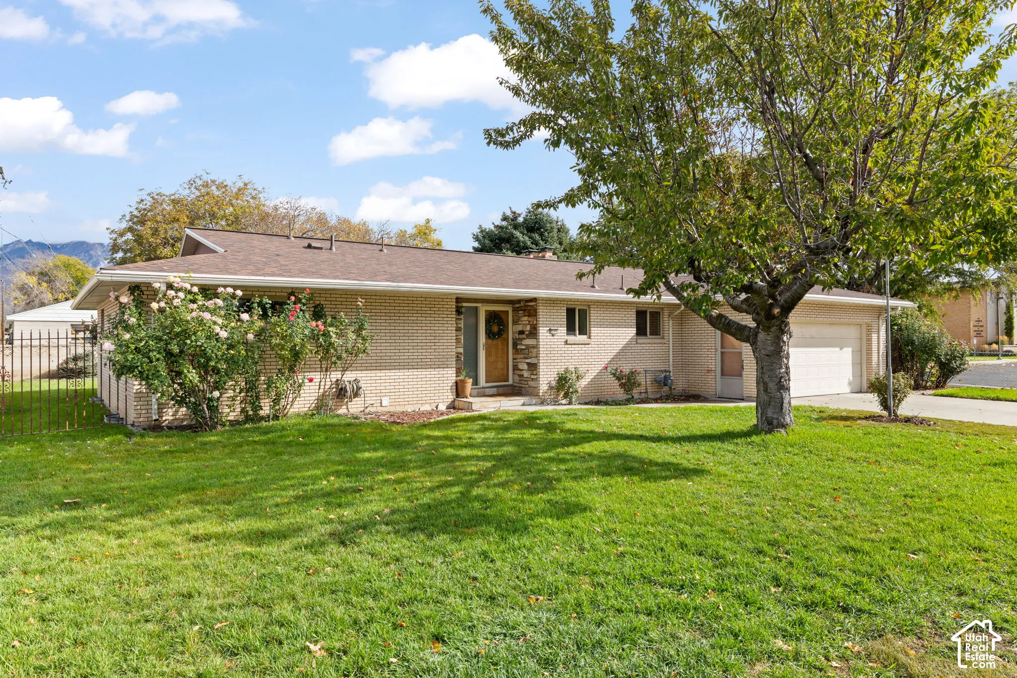 Single-story brick exterior featuring a stone facade entryway, an attached two-car garage, and established landscaping