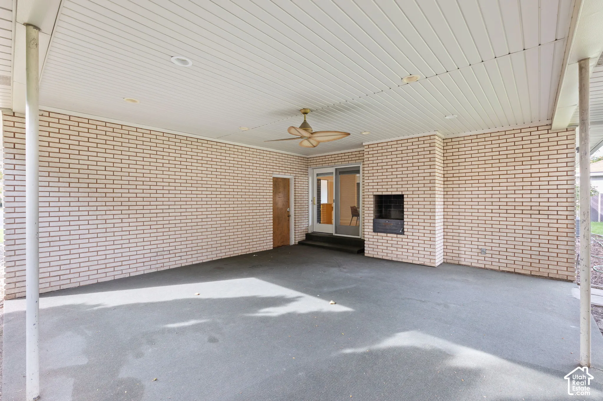 Covered patio featuring brick masonry walls, a concrete floor, recessed ceiling lighting, a ceiling fan, and a built-in outdoor fireplace