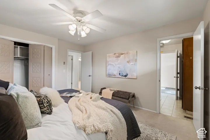 Neutral wall finishes, carpeted flooring, ceiling fan with integrated light fixture, and closet with decorative panel doors