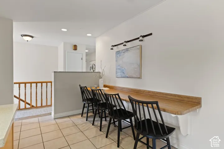 Built-in wall-mounted desk, tile flooring, wood-toned countertop, and three-bulb track lighting