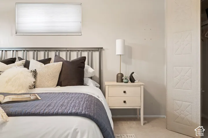 Neutral-toned bedroom featuring an elevated horizontal window, carpeted flooring, and a closet with a decorative textured panel door