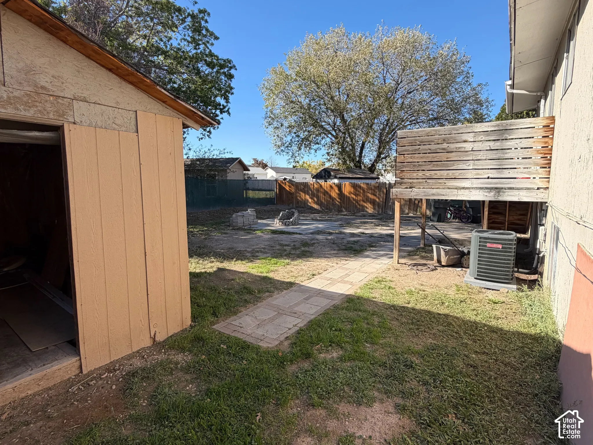 Backyard featuring a wood-sided storage shed, paved walkway, wooden privacy fencing, and an elevated wood deck