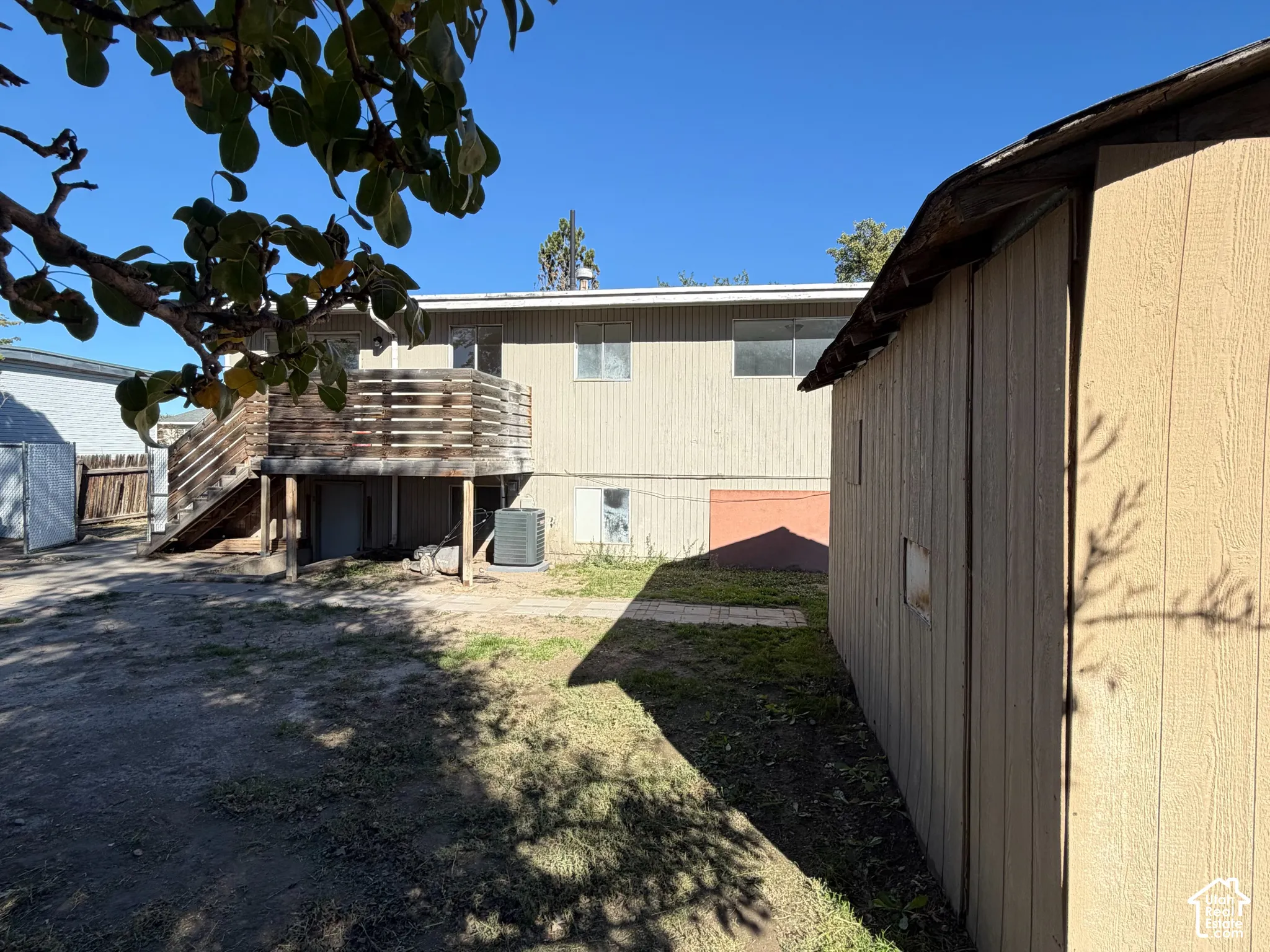 Exterior view featuring a raised wood deck, detached storage structure, and ground-level concrete paver walkway