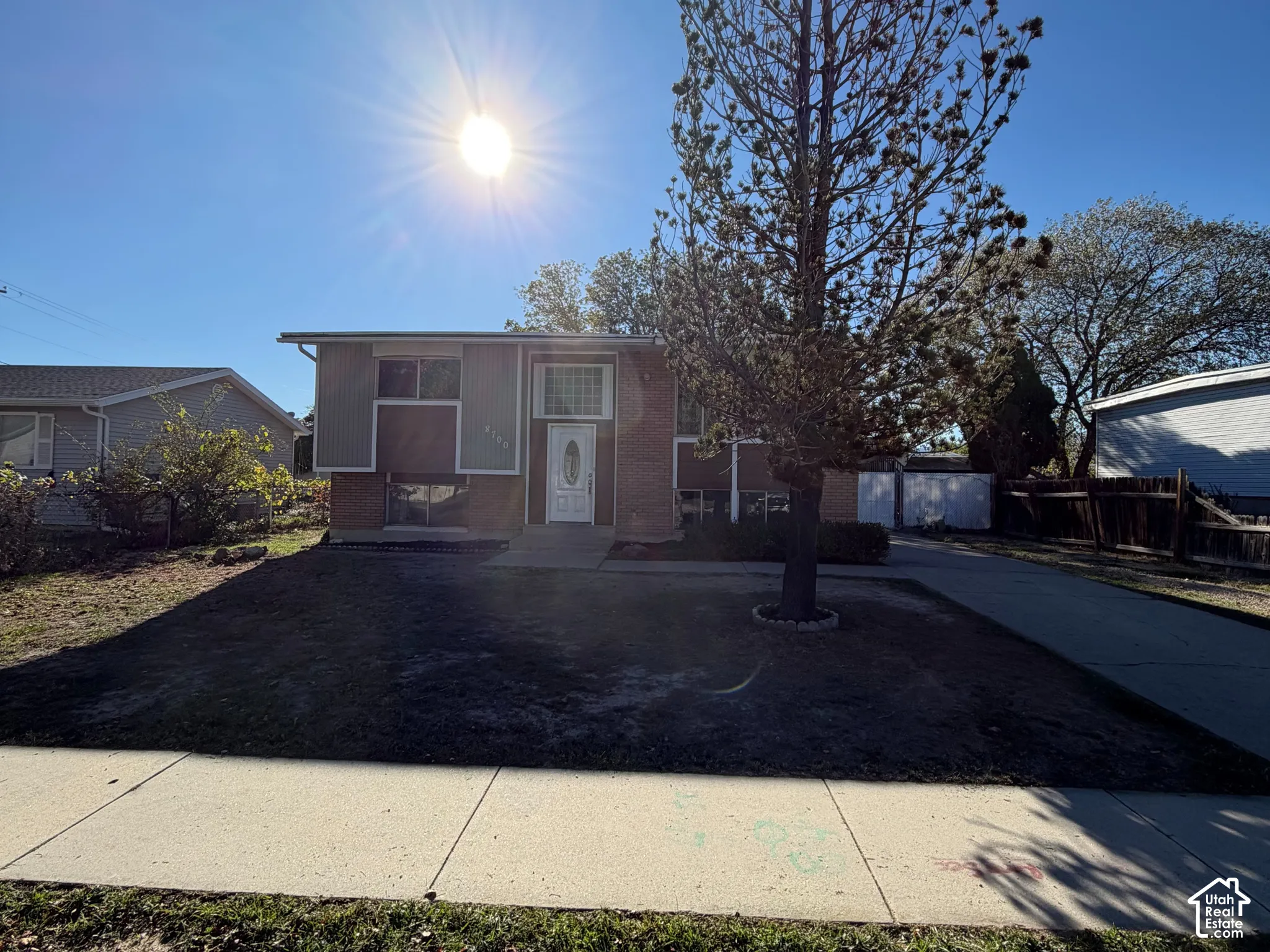 Multi-level exterior featuring a brick and panel facade, front entry door with glass inlay, transom window, and concrete driveway