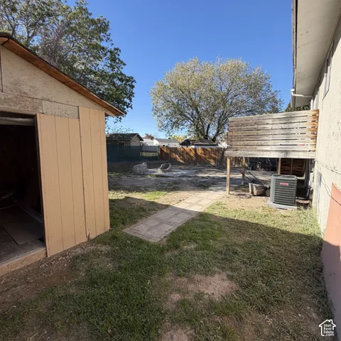 Backyard featuring a wood-sided storage shed, paved walkway, wooden privacy fencing, and an elevated wood deck