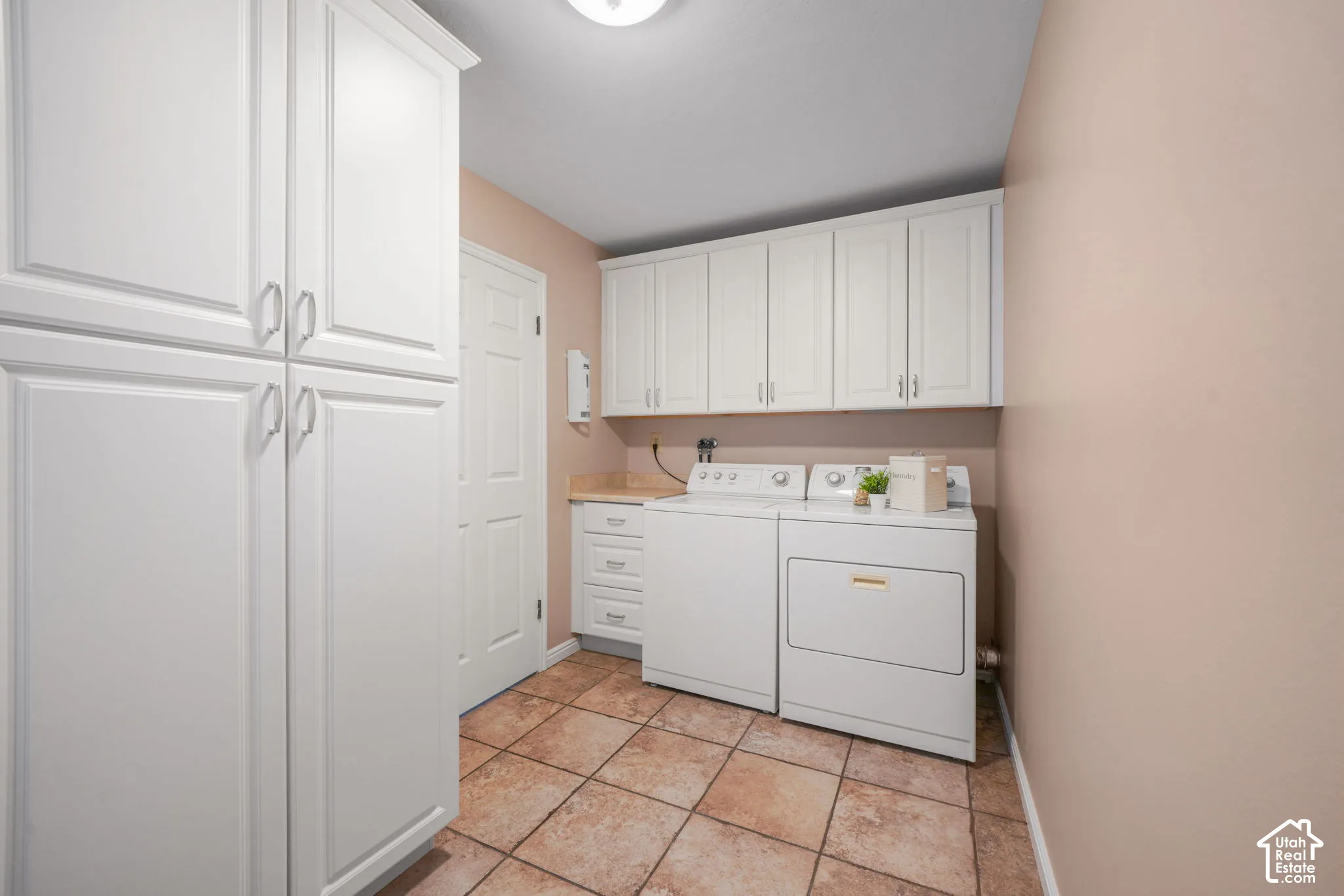Laundry room featuring white cabinetry, stone-finish countertops, tile flooring, and a floor-to-ceiling storage pantry
