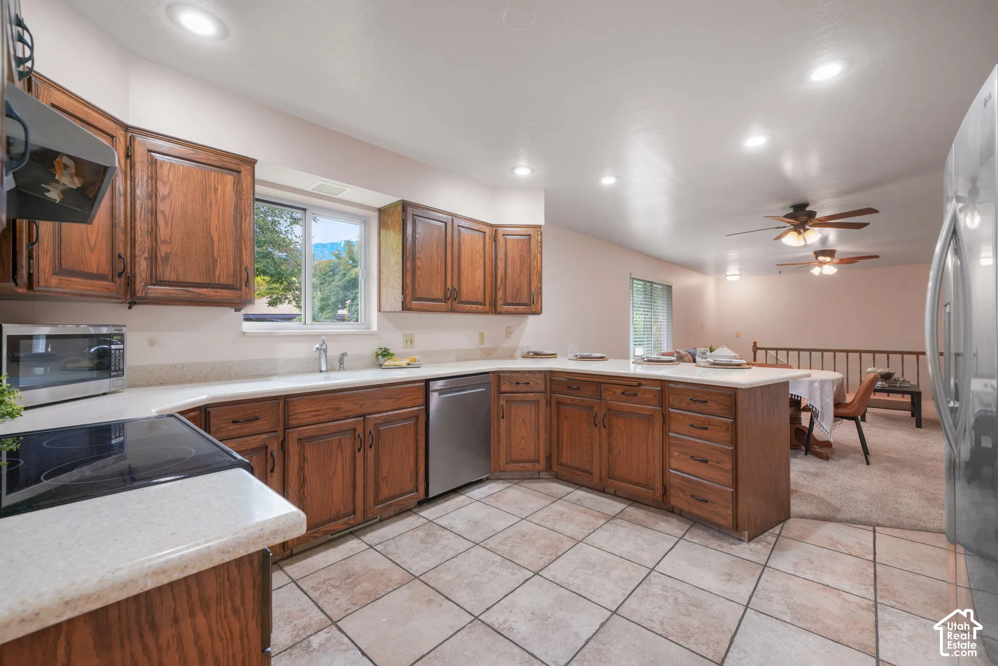 Kitchen featuring wood cabinetry, solid-surface countertops, stainless steel appliances, tile flooring, and recessed lighting