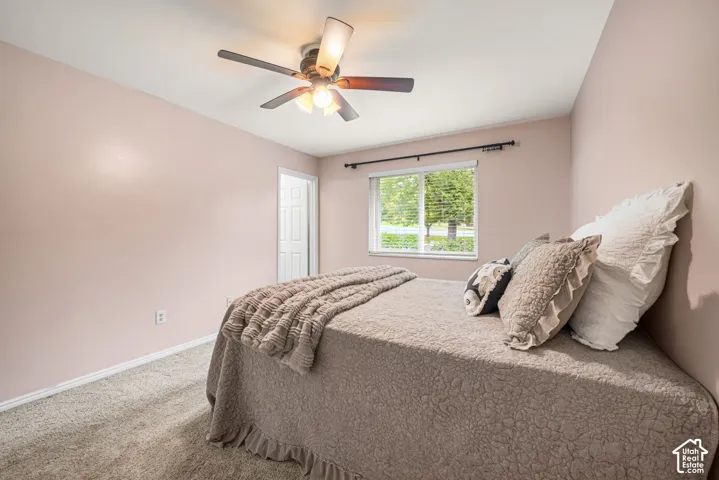 Primary bedroom featuring carpeting, a multi-blade ceiling fan with integrated lighting, a window with a curtain rod, and ensuite bath