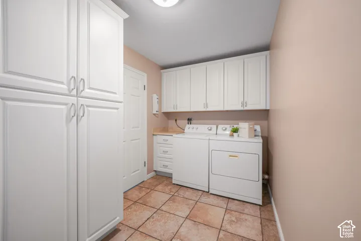Laundry room featuring white cabinetry, stone-finish countertops, tile flooring, and a floor-to-ceiling storage pantry