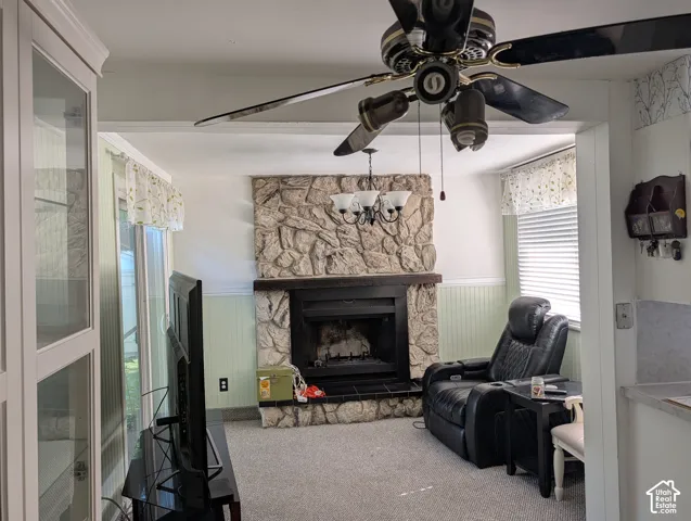 Floor-to-ceiling stone fireplace with a dark timber mantel, beadboard wainscoting, built-in glass-front cabinetry, and a ceiling fan with integrated lighting