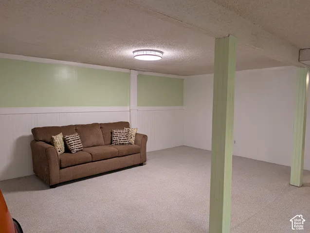 Interior space featuring wall-to-wall carpeting, wainscoting, structural support columns, and a flush-mount ceiling light fixture