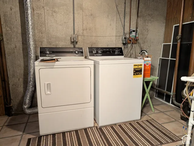 Utility area featuring a top-load washer and front-load dryer with ceramic tile flooring and concrete wall finishes