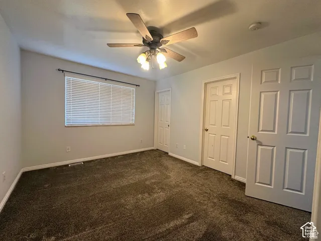 Room featuring neutral carpeting, a central ceiling fan with integrated lighting, and two white six-panel doors