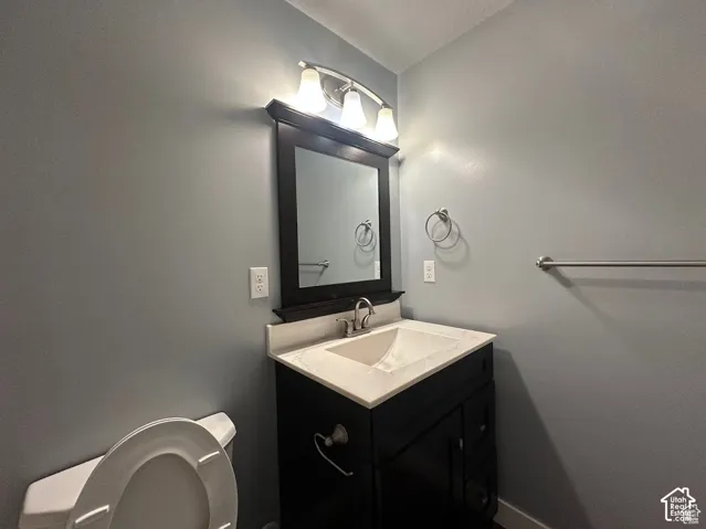 Dark-finish vanity featuring an integrated white sink, stone-composite countertop, three-light polished chrome fixture, and framed wall mirror