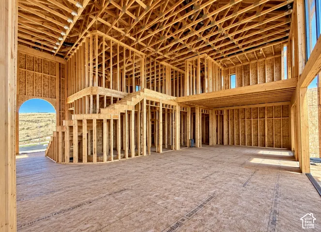 Structural framing featuring vaulted ceilings, an open-concept interior layout, a dedicated staircase structure, and an arched entry