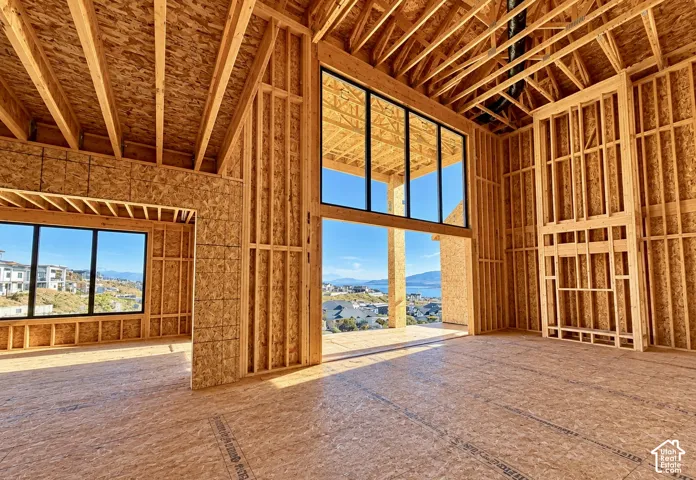 Exposed wood framing with vaulted ceiling, full-height windows, built-in structural fireplace framing, and timber floor joists