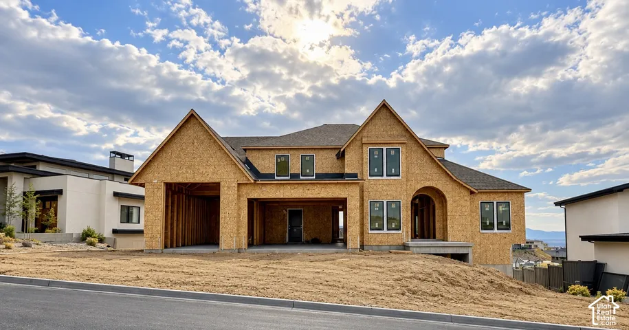 Two-story architectural structure featuring multiple gabled rooflines, a multi-bay garage, an arched covered entry, and large rectangular windows