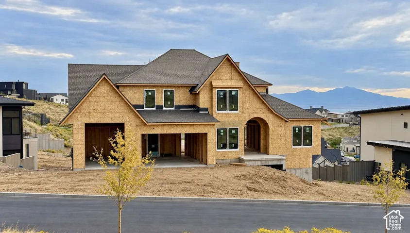 New construction residence featuring multi-gabled rooflines, an arched entryway, structural sheathing exterior, and an attached multi-car garage