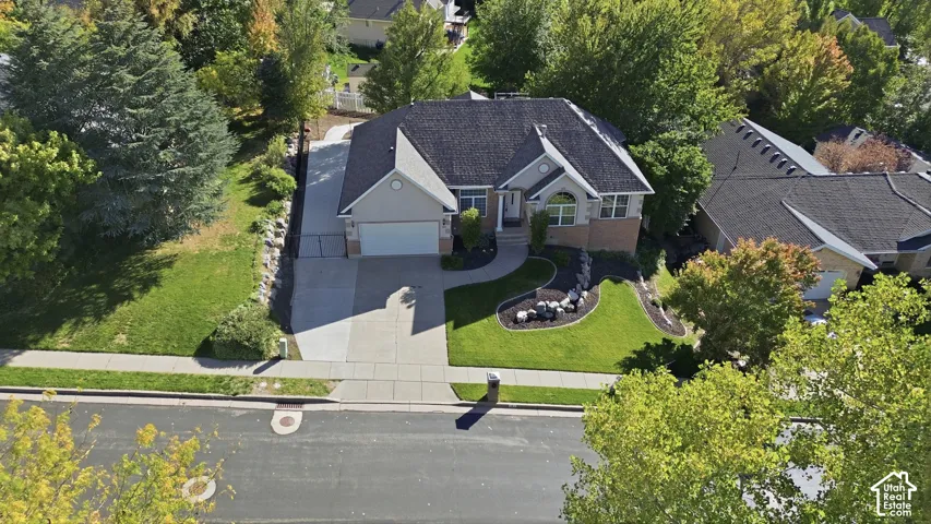 Single-story residence featuring a brick and siding exterior, multi-pitched shingled roof, attached garage, concrete driveway, and landscaped front lawn with boulder accents