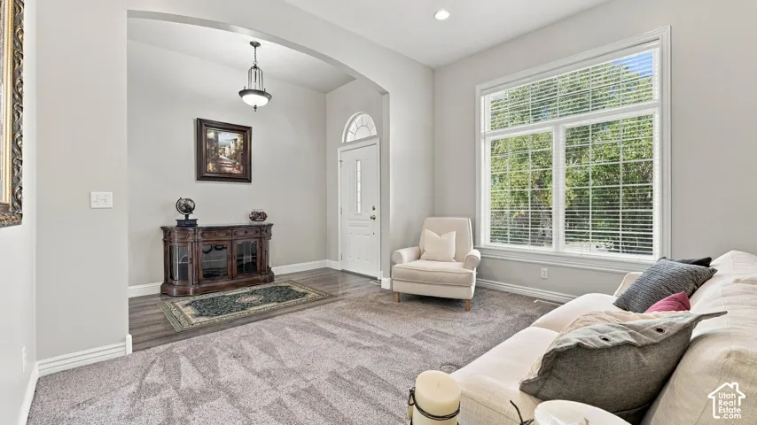 Entryway featuring an arched opening, wood-finish flooring, a pendant light fixture, and a white front door with an arched transom window