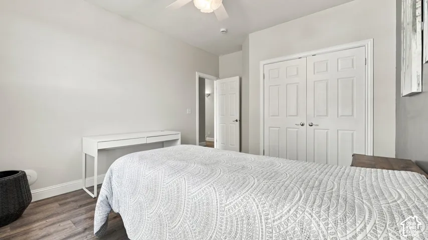 Room featuring wood-finish flooring, a ceiling fan with integrated lighting, and a double-door closet with paneled detail
