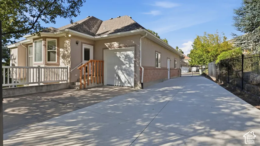 Stucco and brick facade featuring a single-car garage, concrete driveway, and white composite deck with wooden railing