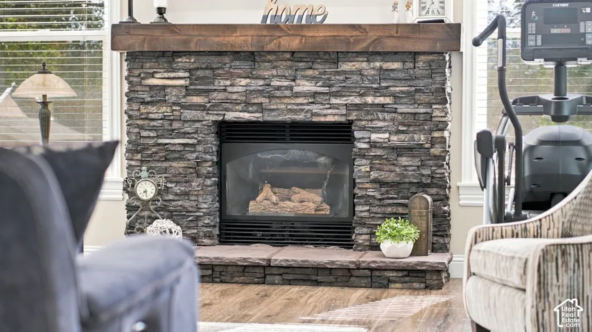 Floor-to-ceiling stone-veneer fireplace featuring a raised hearth and a stained wood mantel